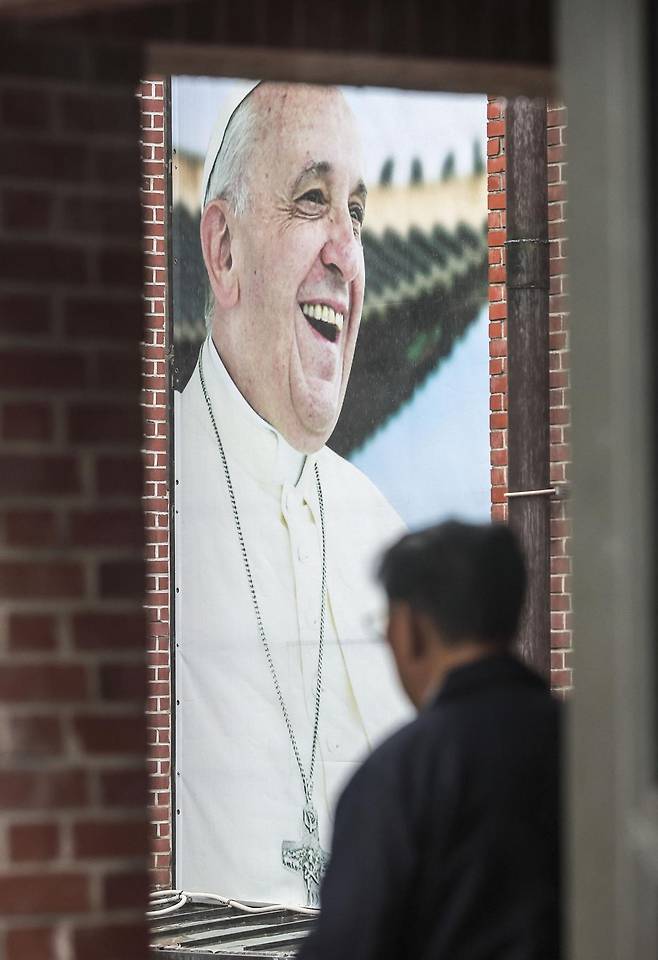 22일 서울 중구 명동대성당에서 신도들이 외벽에 걸린 프란치스코 교황 사진 앞을 지나고 있다. 천주교 서울대교구 주교단은 21일(현지 시간) 선종한 교황의 빈소를 명동대성당에 마련한다. 뉴시스