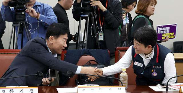 최저임금위원회 류기정(왼쪽) 사용자위원과 이미선 근로자위원이 22일 정부세종청사 고용노동부에서 열린 '2026년 최저임금위원회 제1차 전원회의'에 참석해 악수를 나누는 모습. 뉴스1