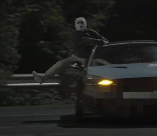 A drag racing suspect performs a stunt while hanging from the passenger seat. [GYEONGGI NAMBU PROVINCIAL POLICE]