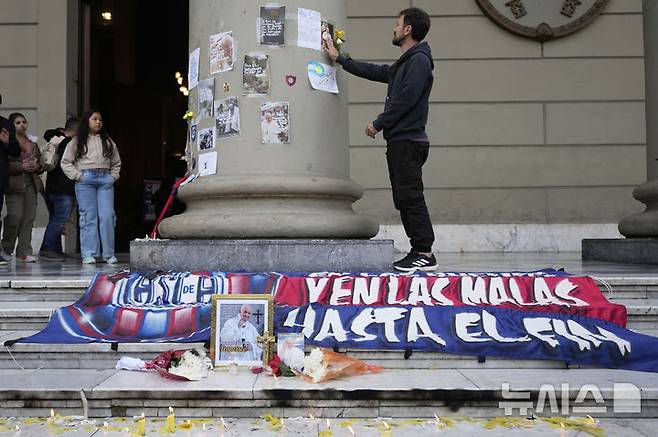 [부에노스아이레스=AP/뉴시스] 21일(현지 시간) 아르헨티나 부에노스아이레스 대성당에서 고(故) 프란치스코 교황의 사진이 축구 클럽 ‘산로렌소’의 배너에 감싸인 채 촛불에 둘러싸여 있다. 프란치스코 교황은 이 클럽의 팬이었다. 2025.04.22.