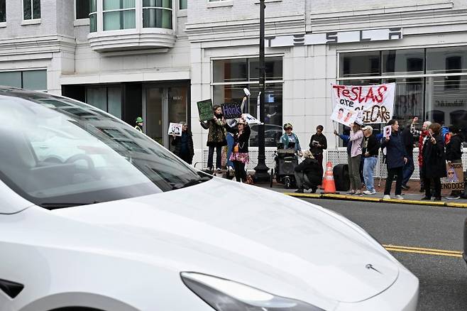 CNBC 설문조사에서 미국인 절반은 테슬라나 일론 머스크 테슬라 최고경영자(CEO)에게 부정적인 것으로 22일(현지시간) 분석됐다. 워싱턴 DC 인근 조지타운의 테슬라 매장 앞에서 12일 머스크 반대 시위가 벌어지고 있다. 로이터 연합