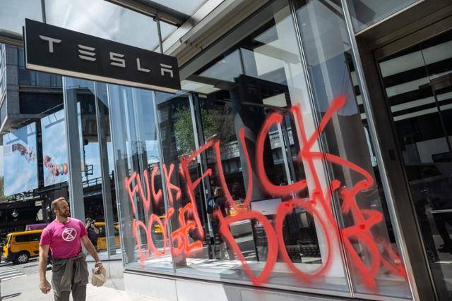 22일 미국 뉴욕의 한 테슬라 전시장 외벽에 일론 머스크 테슬라 최고경영자의 정부효율부 활동을 반대하는 문구가 적혀 있다. 환경단체 멸종저항 회원들이 스프레이로 새긴 것이다. 뉴욕=AFP 연합뉴스