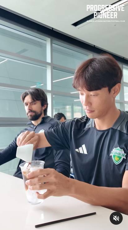 전북 홍정호(오른쪽)가 에스프레소를 뽑은 뒤 얼음을 타 아이스 아메리카노를 만드는 모습을 이탈리아 콤파뇨(왼쪽)가 얼굴을 찡그리며 쳐다보고 있다. [사진 전북 현대 인스타그램]