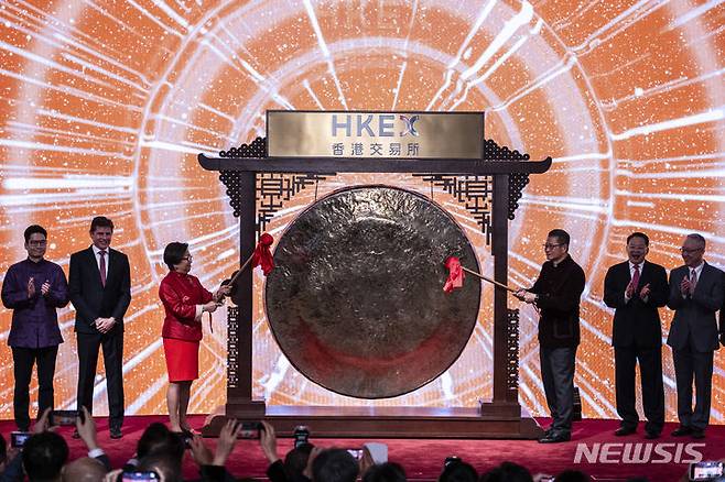 [홍콩=AP/뉴시스] 폴 찬(오른쪽 3번째) 홍콩 재정사장과 로라 차(왼쪽 3번째) 홍콩교역소(증권거래소) 총재가 홍콩 증시 개장을 알리는 징을 치고 있다. 자료사진. 2025.04.23