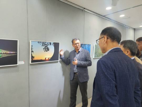 퇴직을 앞둔 차광호(왼쪽) 논산시 부적면장이 논산문화원에서 개최한 '머무르고 싶은 논산' 사진전에서 관람객들에게 작품 설명을 하고 있다. 정종만 기자