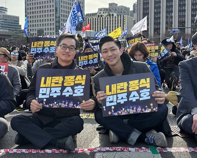 김동연 더불어민주당 대선 경선 후보(왼쪽)와 김대중 전 대통령의 맏손자인 김동연 경기도지사 캠프 김종대 청년·외신대변인(오른쪽)이 지난 3월 서울 광화문에서 열린 집회에서 함께 피켓을 들고 있다. ⓒ김동연 후보 캠프 제공