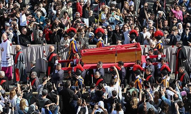 지난 21일(현지시각) 선종한 프란치스코 교황의 관이 23일 거처인 산타 마르타의 집을 떠나 성 베드로 대성당으로 운구되는 동안 추모객들이 지켜보고 있다. 추모객들은 이날부터 오전 7시~자정 사이 조문이 가능하며, 장례식 전날인 25일은 저녁 7시까지 조문을 할 수 있다. 교황의 장례 미사는 26일 오전 10시(한국시각 오후 5시)에 거행된다. 바티칸/AFP 연합뉴스
