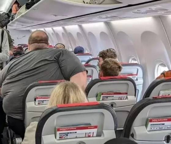 큰 체형의 승객이 항공기 좌석에 힘겹게 앉아 있는 사진이 온라인에 퍼지면서 비행기 가격 논쟁이 불거졌다. 사진 데일리메일 캡처