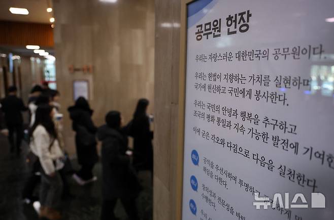 [서울=뉴시스] 배훈식 기자 = 지난 2월 3일 오후 서울 종로구 정부서울청사 로비에 걸린 공무원 헌장 아래로 공무원들이 걸어가고 있다. 2025.02.03. dahora83@newsis.com