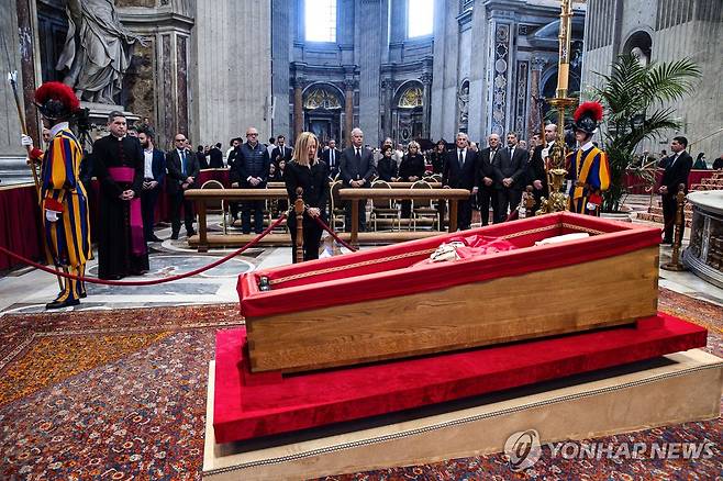프란치스코 교황의 관이 놓인 받침대 (바티칸 EPA=연합뉴스) 23일(현지시간) 조르자 멜로니 이탈리아 총리(가운데)가 바티칸 성 베드로 대성당에 놓인 프란치스코 교황의 관 앞에서 조의를 표하고 있다. 2025.4.23