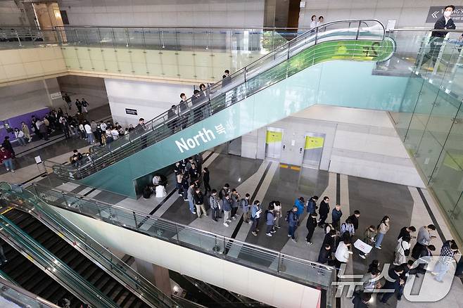 25일 서울 강남구 코엑스 내 입점한 식당에서 화재가 발생해 밖으로 대피했던 관람객들이 전시관 재입장을 위해 줄 서 있다. 이날 오전 11시 7분쯤 코엑스 2층 식당 주방 후드에서 시작된 불은 신고 30분 만인 오후 11시 42분 초진 됐다. 2025.4.25/뉴스1 ⓒ News1 이승배 기자