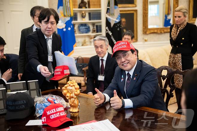 지난 16일(현지시간) 미국 워싱턴DC 백악관 집무실을 찾은 아카자와 료세이 일본 경제재생상이 도널드 트럼프 대통령이 서명해 건넨 '마가(MAGA·미국을 다시 위대하게)' 모자를 써보고 있다. (백악관 제공) ⓒ News1 류정민 특파원