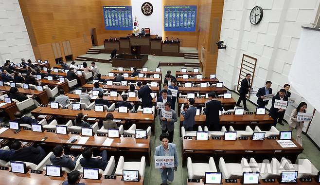 [서울=뉴시스] 추상철 기자 = 25일 오후 서울 중구 서울시의회에서 열린 제330회 시의회 임시회 2차 본회의에서 시의회 야당 의원들이 '입틀막 국민의힘!, 의회독재 강력규탄', '시의회 국민의힘 일 좀 합시다!'라고 적힌 피켓을 들고 퇴장하고 있다. 2025.04.25. scchoo@newsis.com