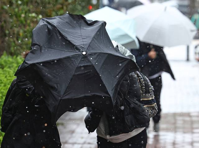 서울 시내에 강풍과 함께 한때 우박이 내린 4월13일 서울 서초구 서울회생법원 인근에서 시민들이 우산 뒤로 몸을 숨기고 있다. 연합뉴스