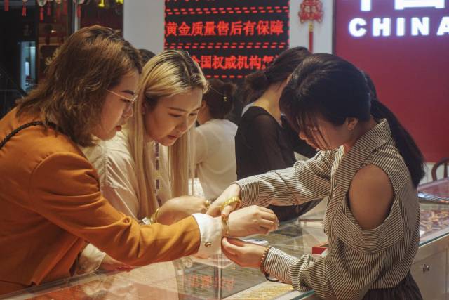 22일 중국 저장성 항저우의 한 금 가게에서 고객들이 금 장신구를 착용해보고 있다. AFP연합