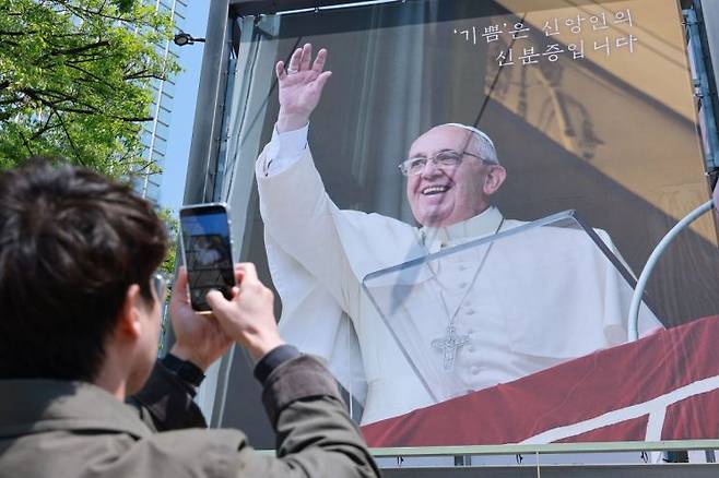 25일 서울 중구 명동대성당을 찾은 시민이 프란치스코 교황 현수막을 촬영하고 있다. 연합뉴스