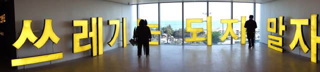 오케이앤피(부산)가 지난 22일부터 열고 있는 ‘세상은 생각보다 허술하게 돌아간다’ 이광기 초대전 풍경. 사진은 관람객이 ‘쓰레기는 되지 말자’ LED 채널 사인(2019)을 돌아보는 모습. 김은영 기자