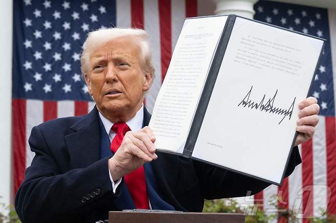 도널드 트럼프 미국 대통령이 지난 2일(현지시간) 워싱턴DC 백악관에서 열린 '미국을 다시 부유하게' 행사에서 상호관세 관련 연설을 한 뒤 서명한 행정명령을 들어 보이고 있다.  ⓒ AFP=뉴스1