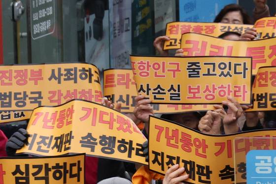 Participants hold signs urging progress in the trial during a citizens' rally organized by the Pohang Earthquake Citizens' Countermeasure Headquarters and 120 social, religious and volunteer groups at Pohang Jungang Market in Pohang, North Gyeongsang, on Nov. 15, 2024. [YONHAP]