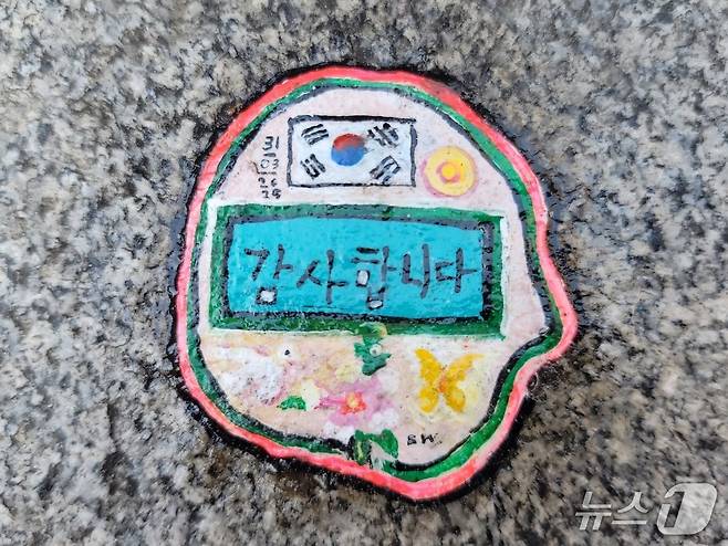 벤 윌슨이 세인트폴 성당에서 밀레니엄 브리지로 이어지는 길목의 한쪽 계단에 만든 위의 껌딱지 작품 안에는 ‘감사합니다’라는 한글과 태극기가 있다. 윌슨은 우측 상단에 한국이 지금의 모든 어려움을 이겨내길 바라는 마음을 담아 해를 그려 넣었다. 아래에는 평화를 상징하는 흰색 비둘기와 무궁화, 위안부 피해자들을 상징하는 노랑나비가 차례로 새겨졌다. @조아현