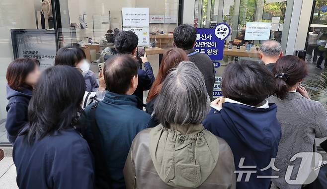 SK텔레콤 가입자 유심(USIM) 정보 해킹 사고 관련 유심 무료교체 서비스 이틀 째인 29일 오전 서울 종로구 T월드 직영 매장 앞에서 번호표를 받지 못한 고객들이 온라인 예약을 하고 있다. 2025.4.29/뉴스1 ⓒ News1 김진환 기자