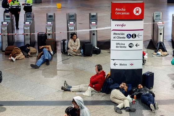 2025년 4월 28일, 이베리아 반도 전체와 프랑스 남부에 영향을 미친 대규모 정전 이후 마드리드 아토차 기차역에서 하룻밤을 보낼 준비를 하는 여행객들이 바닥에 앉거나 누워 있다. AFP=연합뉴스