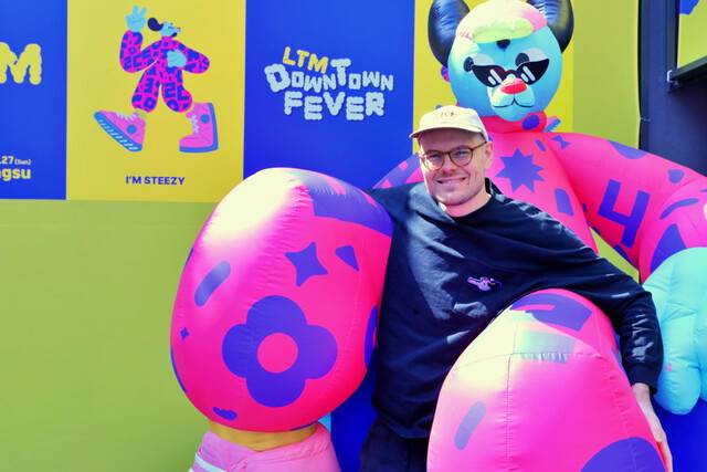 호주 출신 아티스트 브롤가(Brolga)가 지난 25일 서울 성동구 성수동에서 열린 ‘LTM(롯데타운 명동)’ 팝업스토어에서 자신이 디자인한 캐릭터 ‘스티지’의 조형물과 포즈를 취하고 있다. 롯데백화점 제공