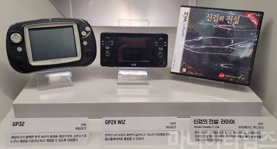 넷마블게임박물관. 국산 휴대용 게임기인 게임파크의 'GP32'(2001년, 왼쪽)와 GP32의 후속기로 알려진 게임파크 홀딩스의 'GP2X WiZ'(2009년, 가운데), 그리고 GP2X WiZ용 게임으로 포팅된 '신검의 전설: 라이어'(2010년, 원작과는 다르게 액션성이 추가됐다). 총 18개의 게임만이 발매됐다. GP32는 사실 PMP(포터블 미디어 플레이어)나 PDA(개인용 디지털 단말기)에 가까운 물건 취급을 받았다. 개발툴이 완전히 공개된 오픈소스를 특징으로 홍보해 에뮬레이터 게임기로도 인기(?)를 끌기도 했다. 참고로 'GP2X'는 게임파크 홀딩스의 제품으로 리눅스 기반 오픈소스 게임기인데, 사실 GP32와 연관성은 없다는 지적도 있다. 게임파크 홀딩스는 게임파크의 유통을 맡기는 했었으나 별개의 회사였으며, GP32와 GP2X는 호환성도 없었기 때문이다. 정신적인 후속기기 정도로 볼 수 있겠다. 이후 'GP2X'의 후속작으로 나온 것이 GP2X WiZ였다. GP2X WiZ는 2009년 당시 이명박 대통령의 '우리는 일본처럼 닌텐도 게임기 같은 걸 못 만드나?'라는 발언 이후 발매돼 '명텐도'라는 별명을 얻기도 했다. GP2X와 GP2X WiZ 역시 게임이 많이 출시되지 않아 게임기로 성공했다고 보기는 어려운데, 국내에서는 영단어학습기로 많이 팔렸다고 한다. 다만 해외에서는 아마추어 개발자들 사이에서 인기를 끌었다고 한다. 여러모로 당시의 시대상을 잘 반영한 게임기다. 참고로 GP2X의 계보는 'CAANOO'(2010년 발매)로 까지 이어졌다. 촬영 : 이동근 기자