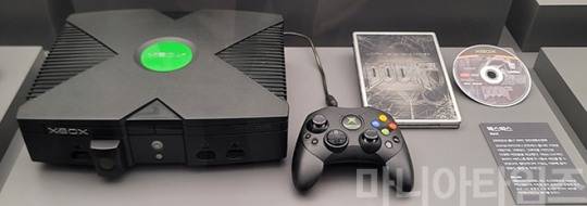 넷마블게임박물관. 2001년 발매된 마이크로소프트의 거치형 콘솔 '엑스박스'. PC용 소프트웨어 시장에서 OS와 압도적인 점유율을 차지하는 오피스 프로그램으로 벌어들인 압도적인 자본력을 바탕으로 개발된 기기로 경쟁기기들을 압도하는 성능을 보여주었다. 가격도 저렴했으며, 매년 가격을 인하까지 했다. 마이크로소프트가 엑스박스 계열 기기를 얼마나 인하해서 팔았으면, 엑스박스 출시 이후 '엑스박스 360'이 출시되기 전까지 단 한 번도 게임 분야에서 수익을 낸 적이 없다. 이처럼 강력한 하드웨어에도 불구하고 게임 소프트의 부족, 마이크로소프트의 게임 산업에 대한 몰이해, 동양권에서의 부진 등으로 성공적으로 평가하기는 어렵다. 판매량은 2470만 대. 우하단의 게임 패키지는 2004년 발매된 엑스박스용 게임인 이드 소프트웨어의 '둠 3'. 촬영 : 이동근 기자