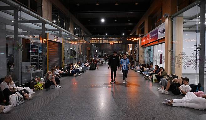 스페인 코르도바에서 28일(현지시간) 저녁 관광객들이 갑작스런 대규모 정전 사태를 맞아 거리의 바닥에 앉아 시간을 보내고 있다. [AFP]