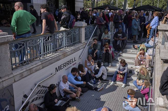 [바르셀로나=AP/뉴시스] 28일(현지 시간) 스페인에서 대규모 정전 사태가 발생해 바르셀로나 시민들이 폐쇄된 지하철역 밖에서 운행 재개를 기다리고 있다. 이날 스페인과 포르투갈에서 발생한 대규모 정전으로 기차, 지하철, 항공기 등 주요 교통수단이 마비되며 피해가 잇따랐다.  2025.04.29.