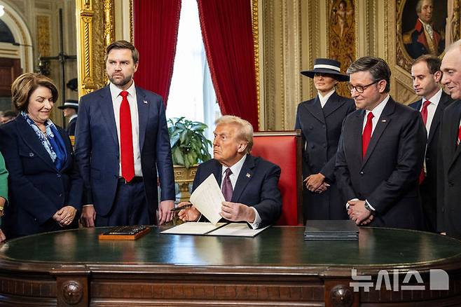 [워싱턴=AP/뉴시스] 도널드 트럼프(가운데) 미국 대통령이 취임 첫날인 1월 20일(현지 시간) 워싱턴 연방의회 의사당 로툰다홀에서 취임식을 마친 후 의사당 내 '대통령의 방'으로 자리를 옮겨 신임 대통령 서명 행사를 하고 있다. 트럼프 대통령은 100일간 행정명령 137건을 내렸다. 2025.04.29.
