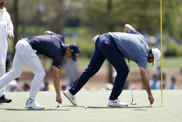 2라운드에 같은 조로 경기한 저스틴 토머스(왼쪽)와 스코티 셰플러가 나란히 그린 위 피치마크를 수리하고 있다. EPA연합뉴스