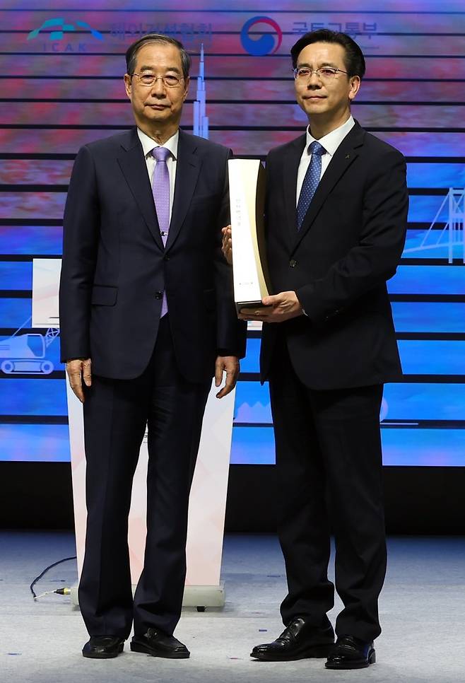 한덕수 대통령 권한대행 국무총리가 29일 서울 강남구 건설회관에서 열린 해외건설 1조달러 수주 및 60주년 기념식에서 이한우 현대건설 대표이사에게 해외건설의 탑을 수여 뒤 기념촬영하고 있다. 사진=뉴시스
