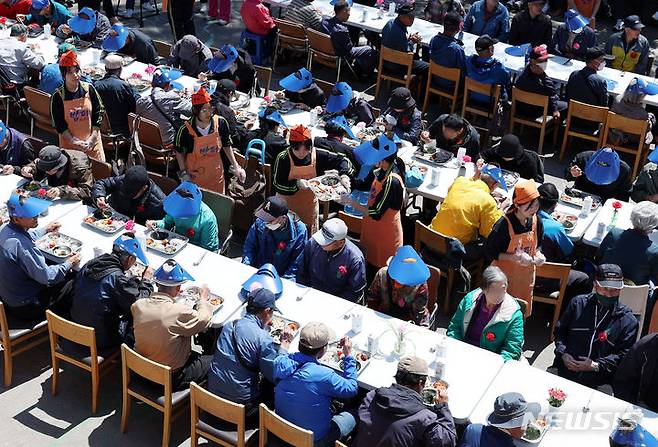 [서울=뉴시스] 추상철 기자 = 어버이날인 8일 오전 서울 동대문구 밥퍼나눔운동본부 앞마당에서 열린 다일공동체의 '어버이날 효도잔치'에서 자원봉사자들이 어르신에게 무료배식을 하고 있다. 2024.05.08. scchoo@newsis.com