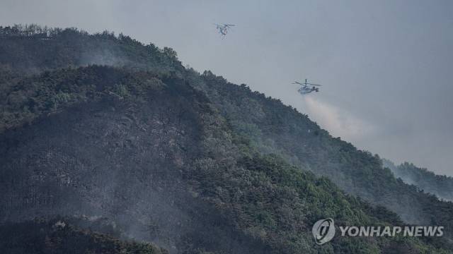 ▲ 대구 대형 산불 발생 이틀째인 29일 대구 북구 산불 현장의 산림이 잿더미가 된 가운데 헬기가 물을 투하하고 있다. ⓒ 연합뉴스