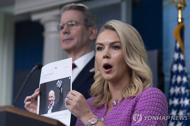 29일(현지시간) 제프 베이조스 아마존 창업자 사진이 첨부된 로이터 기사 내용 들어 보이는 캐롤라인 레빗 백악관 대변인  [AP=연합뉴스. 재판매 및 DB 금지]