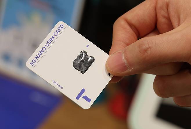 An SK Telecom employee holds up a SIM card at the mobile carrier's branch in Seoul on April 25. [YONHAP]