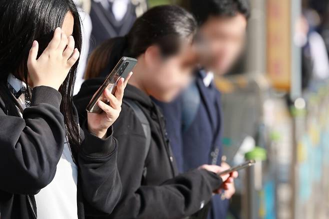 서울 시내 한 중학교에서 하교하는 학생이 스마트폰을 사용하고 있다. 연합뉴스