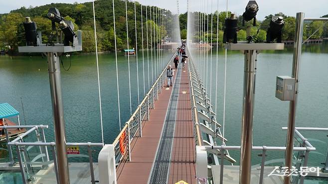 예산 예당호 출렁다리를 걸어가는 관광객들. 성인 3150명을 동시에 수용할 수 있는데, 바다 위 배처럼 부드럽게 출렁이는 다리는 걷는 재미가 있다         충남｜김재범 기자 oldfield@donga.com