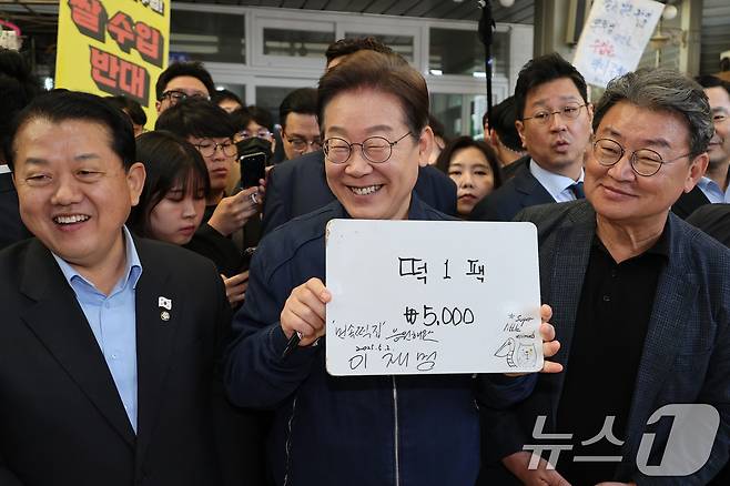 '골목골목 경청투어 : 접경벨트편'에 나선 이재명 더불어민주당 대통령 후보가 2일 오전 강원 철원군 동송전통시장에 위치한 떡집에 들러 가격판에 서명을 한 뒤 미소를 짓고 있다. (공동취재) 2025.5.2/뉴스1 ⓒ News1 이재명 기자