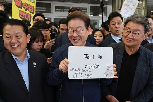 더불어민주당 이재명 대선 후보가 '골목골목 경청투어' 접경지역 방문 이틀째인 2일 강원도 철원군 동송전통시장에서 한 떡집에 들러 가격판에 사인을 해준 뒤 활짝 웃고 있다. 2025.5.2 [사진=연합뉴스]