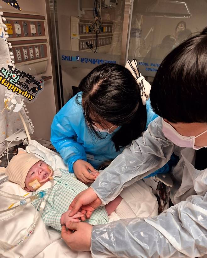 지난 2월 경기도 성남시 분당서울대병원 중환자실에 입원해 있는 윤솔(0)군을 사랑스럽게 쳐다보고 있는 부모의 모습. 안지은씨 제공