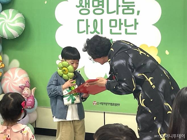1일 낮 12시 서울 서대문구 사랑의장기기증운동본부에서 장기기증인 유가족이 심장이식인 어린이 강윤호군(9)에게 어린이날 선물을 건네고 있다./사진=이현수 기자.