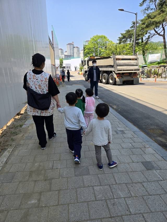 서울보건환경연구원 어린이집에 다니는 어린이들이 인도를 따라 걷고 있다.  원아들은 인근 재개발 공사 현장에 투입되는 대형 트럭들 때문에 보행 안전에 위협을 받으며 야외활동에도 지장을 받고 있다고 호소했다. 독자 제공