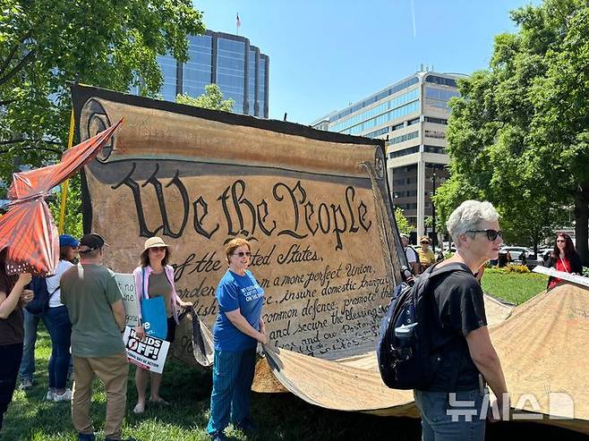 [워싱턴=뉴시스]이윤희 특파원 =국제 노동절인 1일(현지 시간) 미국 전역에서는 도널드 트럼프 행정부에 반대하는 집회가 동시다발적으로 벌어진 가운데, 미국 워싱턴DC 백악관 인근 프랭클린 공원에서 열린 '메이 데이' 집회에서 미국 헌법 모양의 대형 천막을 참가자들이 들어올리고 있다. 2025.05.02.