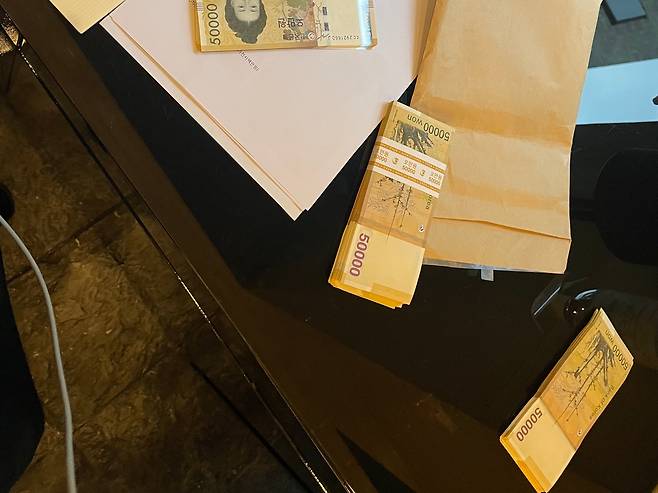 2021년 6월 문재인 전 대통령의 부인 김정숙 여사의 맞춤 의상 옷값으로 지불됐다는 현찰과 관봉권의 모습. A4 용지에는 김 여사가 구매해 간 것으로 추정되는 258만원 상당의 코트, 178만원 상당 재킷, 88만원 상당 슬렉스 등 제품명이 줄줄이 적혀 있다. /본지 입수