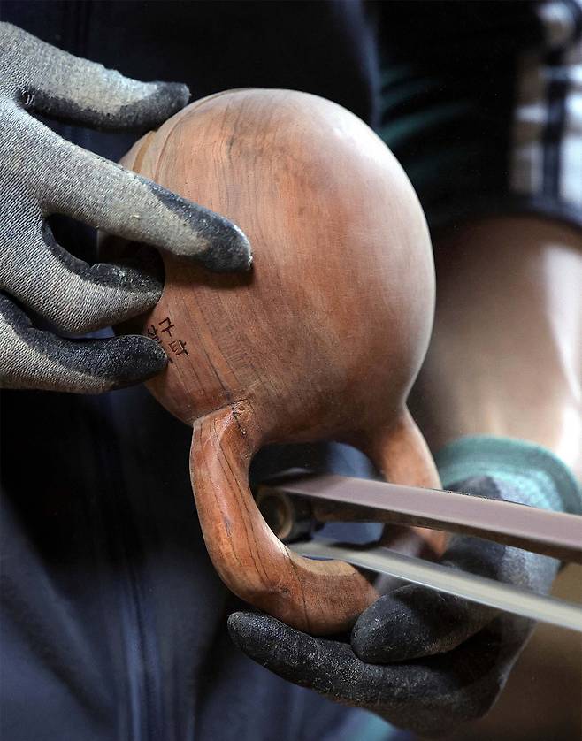 ② 목탁의 표면을 사포로 다듬고 있다.