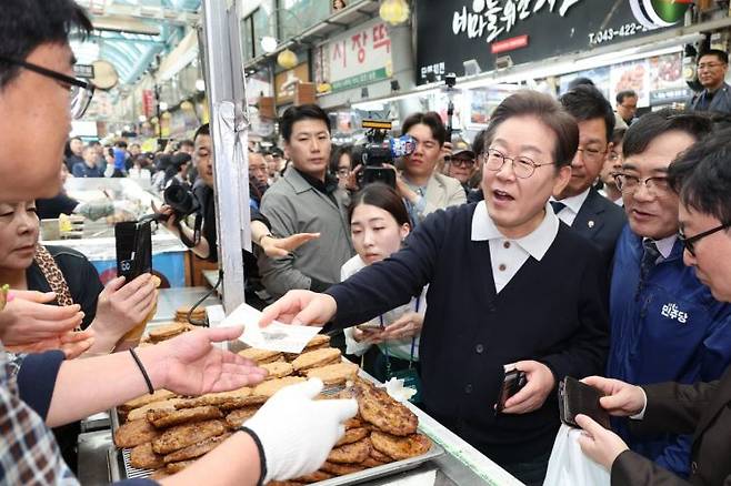 이재명 더불어민주당 대선후보가 '골목골목 경청투어' : 단양8경편'에 나선 4일 충북 단양군 단양구경시장에서 떡갈비를 사먹으면서 지역화폐를 사용하고 있다. 연합뉴스.