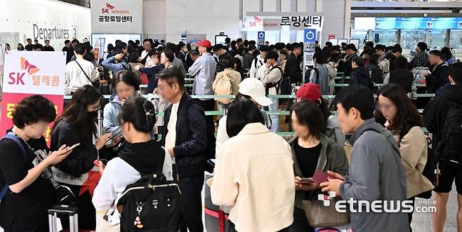 6일 간의 황금연휴가 시작된 1일 인천국제공항 1터미널 출국장에서 SK텔레콤을 이용하는 여행객들이 유심 교체를 위해 줄지어 서 있다. 인천국제공항공사는 6일까지 공항 이용객이 약 148만 명에 달할 것으로 예상되며, 오는 3일 약 21만 여명의 이용객이 몰리며 최대 혼잡이 예상된다고 밝혔다. 이동근기자 foto@etnews.com